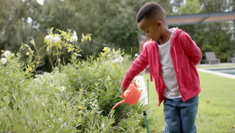 Afroamerikanischer-Junge-Gießt-Pflanzen-Im-Sonnigen-Garten-In-Zeitlupe