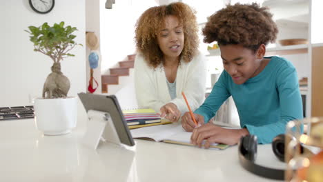 African-american-mother-helping-her-son-with-homework-using-tablet-in-kitchen,-slow-motion