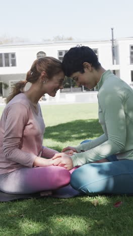 Feliz-Pareja-De-Lesbianas-Caucásicas-Practicando-Yoga-En-Un-Jardín-Soleado,-Cámara-Lenta