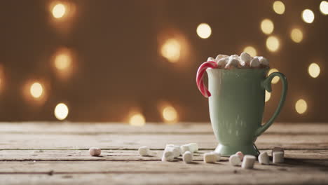 Video-of-mug-of-chocolate,-marshmallows,-christmas-decorations-and-copy-space-on-wooden-background