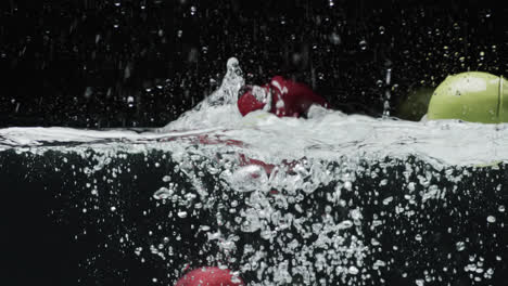Video-Von-Äpfeln,-Die-Ins-Wasser-Fallen,-Mit-Kopierraum-Auf-Schwarzem-Hintergrund