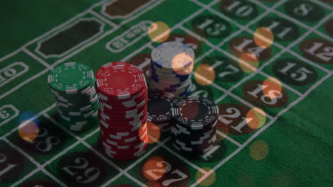 Animation-of-spots-of-light-over-close-up-of-a-stack-of-casino-poker-chips-on-a-table