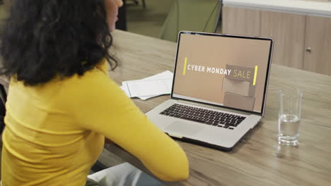 Biracial-woman-at-table-using-laptop,-online-shopping-on-cyber-monday-sale-day,-slow-motion