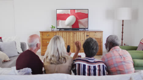 Diverse-senior-friends-watching-tv-with-rugby-ball-on-flag-of-england-on-screen