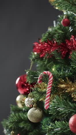 Vertical-video-of-christmas-tree-with-candy-cane-and-decorations-and-copy-space-on-black-background