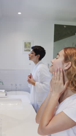 Happy-caucasian-lesbian-couple-looking-in-mirror-and-touching-face-in-bathroom