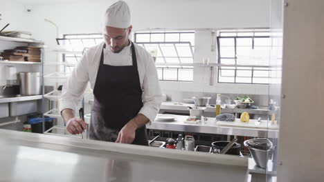 Focused-caucasian-male-chef-preparing-meal-in-kitchen,-slow-motion