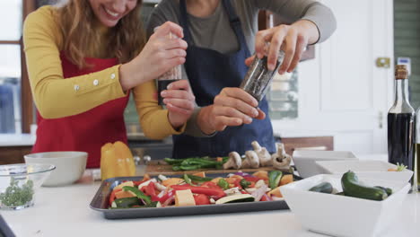 Happy-caucasian-lesbian-couple-preparing-food-in-sunny-kitchen