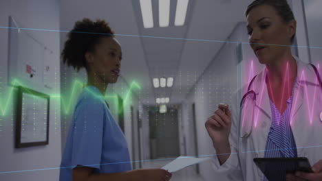 Animation-of-heart-rate-monitor-over-diverse-female-doctor-and-health-worker-discussing-at-hospital