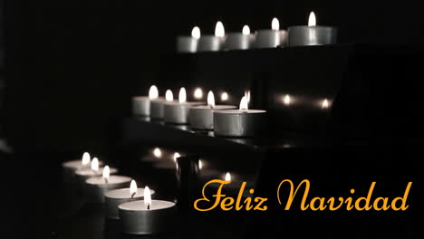 Animation-of-feliz-navidad-text-over-burning-set-of-candles-against-black-background
