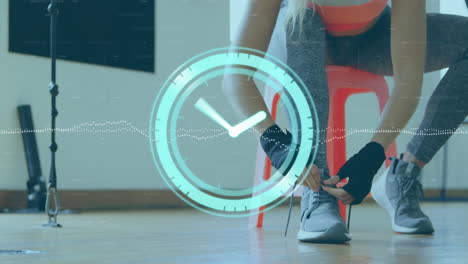 Animation-of-neon-ticking-clock-against-mid-section-of-female-boxer-tying-shoes-laces-at-the-gym