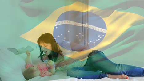 Composite-Video-Einer-Wehenden-Brasilianischen-Flagge-Vor-Einer-Kaukasischen-Mutter,-Die-Mit-Ihrer-Tochter-Zu-Hause-Spielt