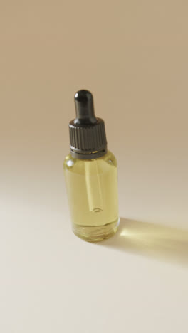 Vertical-video-of-close-up-of-glass-bottle-with-pump-and-copy-space-on-beige-background