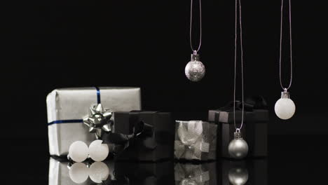 Video-of-silver-baubles-christmas-decorations-and-gifts-with-copy-space-on-black-background