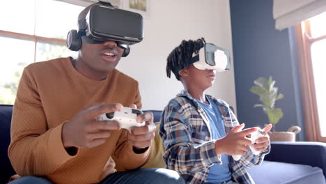 Afroamerikanischer-Vater-Und-Sohn-Spielen-Videospiele-Mit-VR-Headsets-Zu-Hause,-Zeitlupe