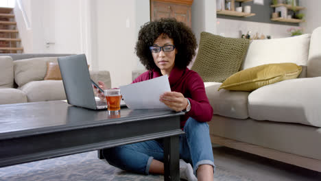 Happy-biracial-woman-using-laptop-and-smartphone-at-home,-slow-motion