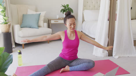 Feliz-Mujer-Asiática-Haciendo-Yoga-Y-Estirándose-En-El-Dormitorio,-En-Cámara-Lenta