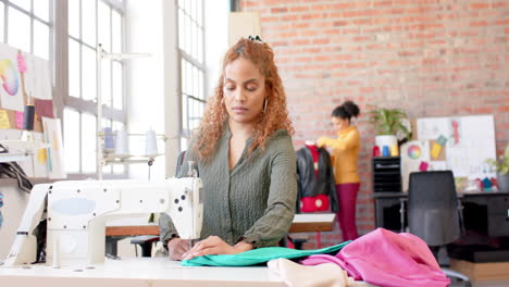 Biracial-female-fashion-designer-sewing-fabric-with-sewing-machine-in-studio,-slow-motion