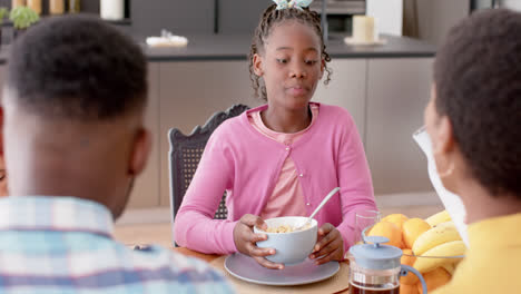 African-american-parents-and-daughter-eating-breakfast-at-table-in-kitchen,-slow-motion
