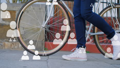 Animation-Von-Personengruppen-Symbolen-über-Dem-Unteren-Teil-Einer-Person,-Die-Auf-Der-Straße-Ein-Fahrrad-Fährt