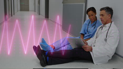 Animation-of-heart-rate-over-diverse-male-female-doctors-discussing-sitting-on-floor-at-hospital