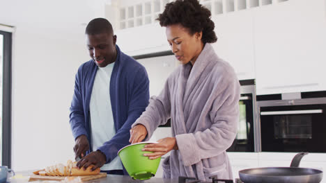 Video-of-happy-african-american-couple-preparing-breakfast-together-in-kitchen