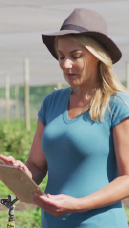 Video-of-caucasian-woman-with-laptop-standing-in-greenhouse