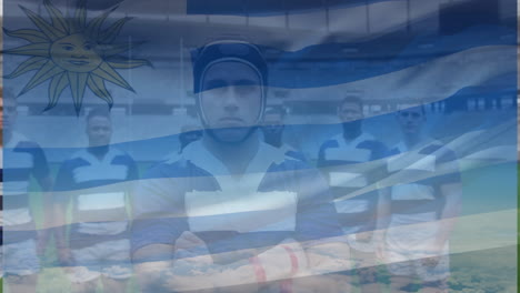Animation-of-uruguay-flag-over-team-of-diverse-male-rugby-players-standing-together-at-rugby-field