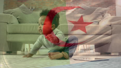 Composite-Video-Einer-Wehenden-Algerischen-Flagge-Vor-Einem-Afroamerikanischen-Baby,-Das-Zu-Hause-Auf-Dem-Boden-Spielt