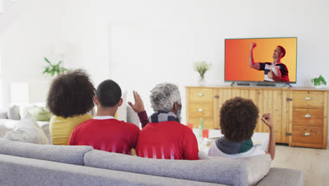 Biracial-family-watching-tv-with-caucasian-male-rugby-player-with-ball-on-screen