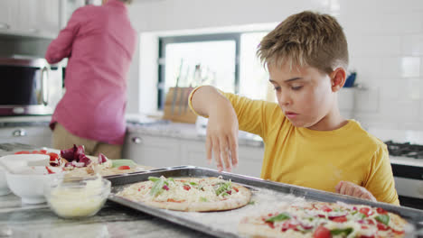 Happy-caucasian-grandfather-and-grandson-making-pizza-in-kitchen,-slow-motion