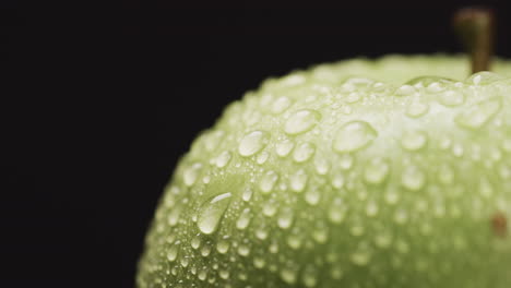 Close-up-of-water-droplets-on-the-surface-of-a-green-apple,-with-copy-space