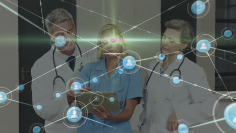 Animation-of-icons-connected-with-lines-over-caucasian-doctors-discussing-over-digital-tablet
