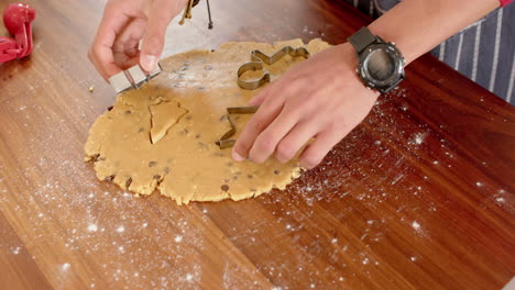Biracial-man-wcutting-christmas-cookies-in-kitchen-at-home,-slow-motion