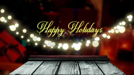 Animation-of-happy-holidays-text-and-hanging-fairy-lights-over-wooden-plank-against-decorated-house