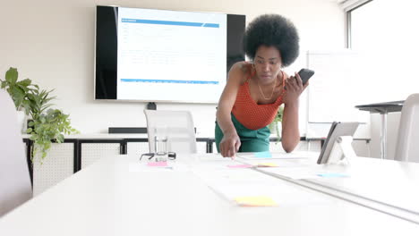African-american-casual-businesswoman-and-talking-on-smartphone-in-board-room,-slow-motion