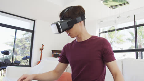 Asiatischer-Junge-Mit-VR-Headset-Gestikuliert-Im-Wohnzimmer-Zu-Hause