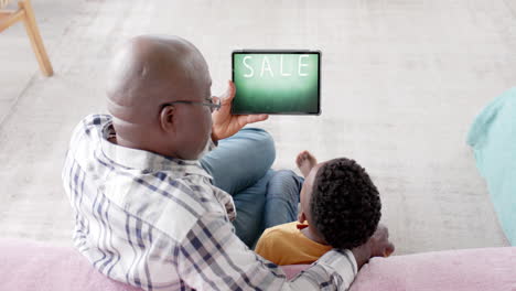 African-american-grandfather-and-grandson-using-tablet,-online-shopping-during-sale,-slow-motion