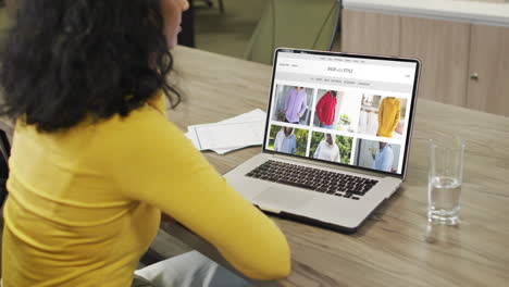 Biracial-Frau-Am-Tisch-Mit-Laptop,-Online-Shopping-Für-Kleidung,-Zeitlupe