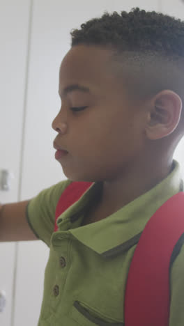 Video-of-african-american-boy-closing-locker-and-smiling-at-school