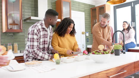 Happy-diverse-male-and-female-friends-preparing-food-together-in-kitchen