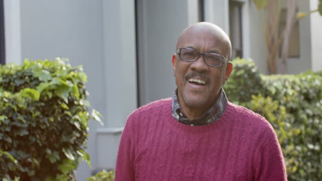Porträt-Eines-Glücklichen-älteren-Afroamerikanischen-Mannes-Mit-Brille,-Der-Im-Sonnigen-Garten-Lacht,-Zeitlupe