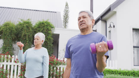 Happy-senior-diverse-couple-exercising-in-garden