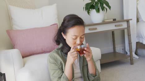 Happy-asian-woman-drinking-tea-in-bedroom,-in-slow-motion