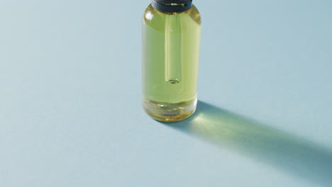 Close-up-of-glass-bottle-with-pump-with-copy-space-on-blue-background
