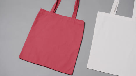 Close-up-of-red-and-white-bags-on-grey-background,-with-copy-space,-slow-motion