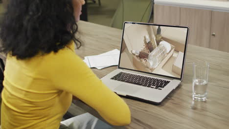 Biracial-woman-at-table-using-laptop,-online-shopping-for-beauty-products,-slow-motion