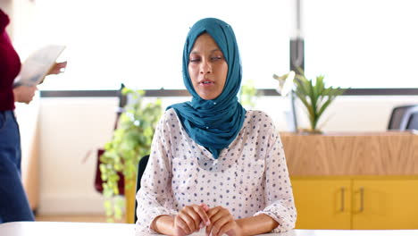 Mujer-De-Negocios-Casual-Birracial-Con-Hijab-Haciendo-Videollamadas-En-La-Oficina,-Cámara-Lenta