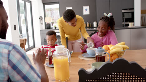 African-american-parents-with-son-and-daughter-eating-breakfast-at-table-in-kitchen,-slow-motion