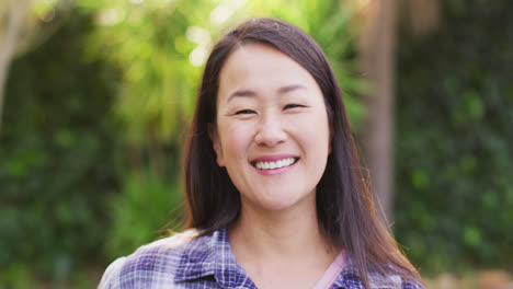 Video-Eines-Porträts-Einer-Glücklichen-Asiatischen-Frau,-Die-Im-Garten-Posiert